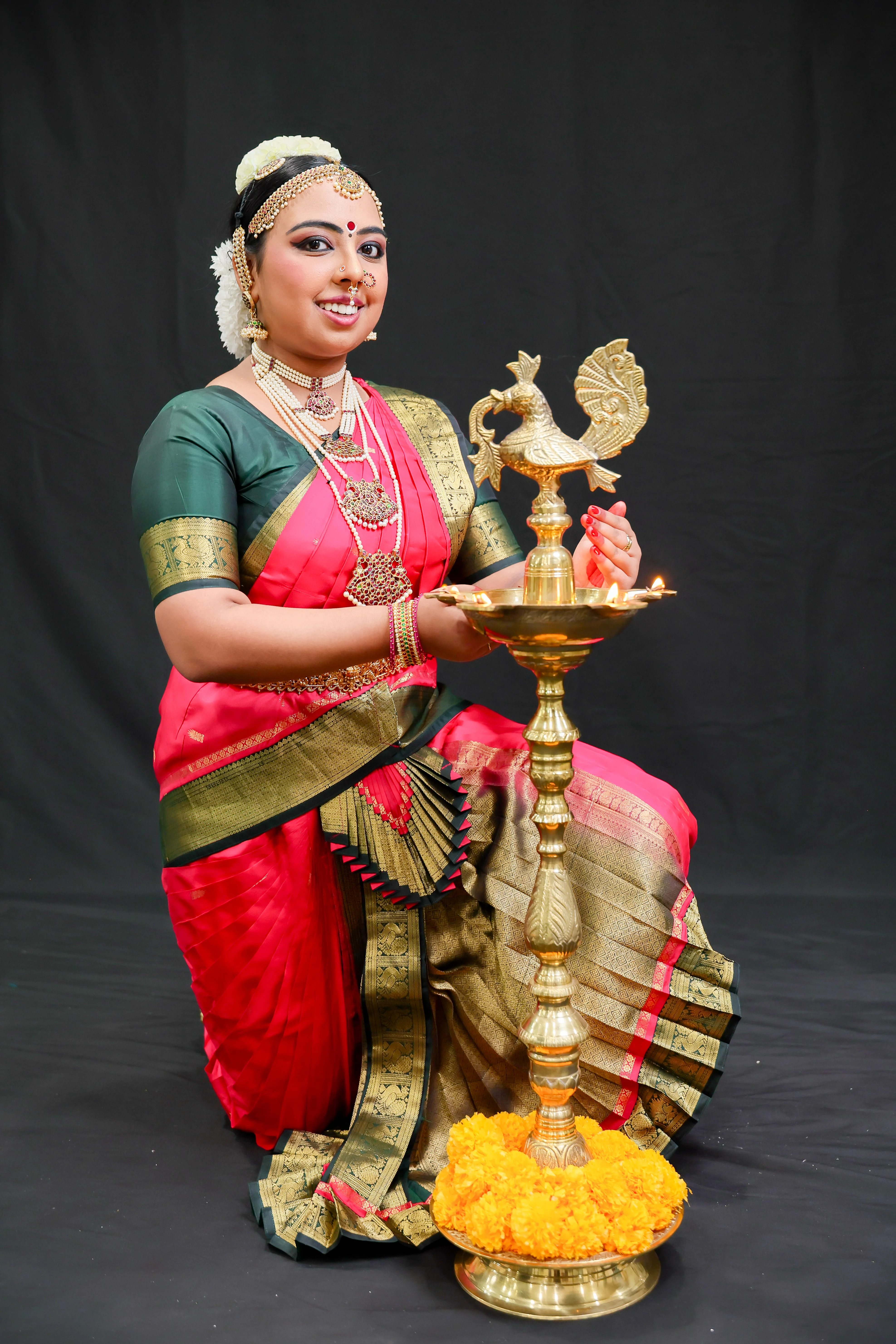 Shreya Sreejith seated beside the brass lamp, smiling with marigolds